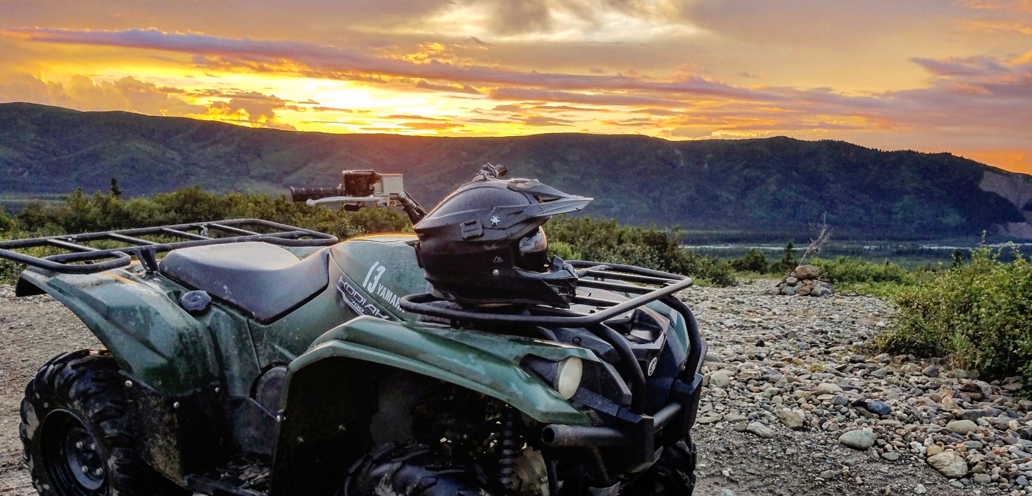 atv parked with a helmet during a denali sunset